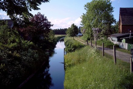 zeigt Graben neben einem Weg und angrenzender Bebauung
