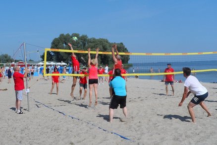 zeigt am Strand Menschen, die Volleyball spielen