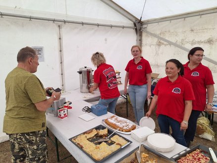 zeigt Kuchenstand mit Frauen beim Verkauf