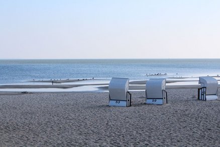 zeigt Blick auf einen menschenleeren Strand mit einigen Strandkörben und das Haff