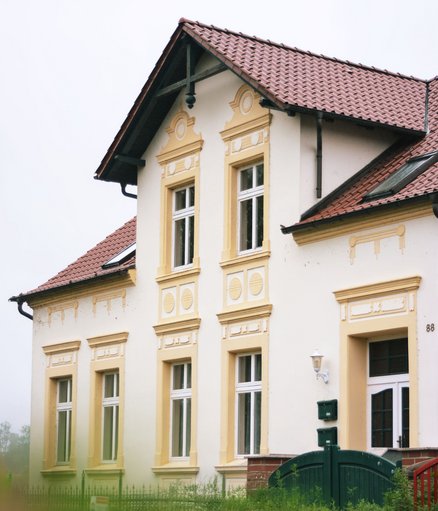 zeigt ein Kapitänshaus mit farbig abgesetzten Stuckelementen in der Putzfassade und Zwerchgiebel