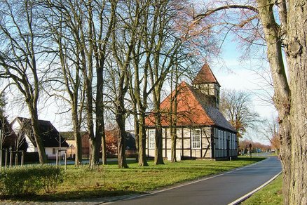 zeigt Straße mit Bäumen und einer Fachwerkkirche