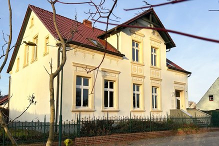 zeigt ein Kapitänshaus mit farbig abgesetzten Stuckelementen in der Putzfassade und Zwerchgiebel
