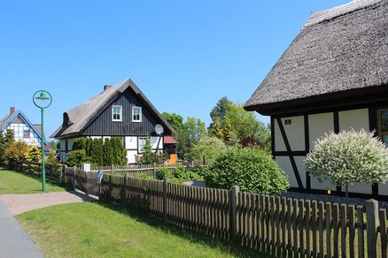 zeigt Blick auf mehrere Fachwerkhäuser mit Garten entlang einer Straße