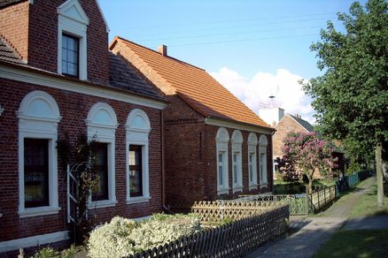 zeigt mehrere Gründerzeitgebäude aus rotem Klinker mit kleinem Vorgarten, davor ein gepflasterter Gehweg