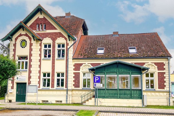 Liebevoll saniertes Gründerzeitgebäude in der Ortsmitte - ein kleines Schmuckstück. Hier hat die Kindertagesstätte der Gemeinde ihr Domizil gefunden. zeigt Ansicht eines Gründerzeitgebäudes in Klinkerbauweise und mit Fassadenzierelementen