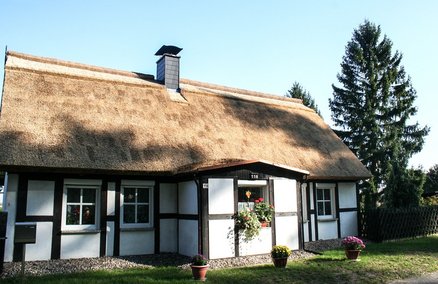 zeigt ein Wohnhaus mit Fachwerk und Schilfdach