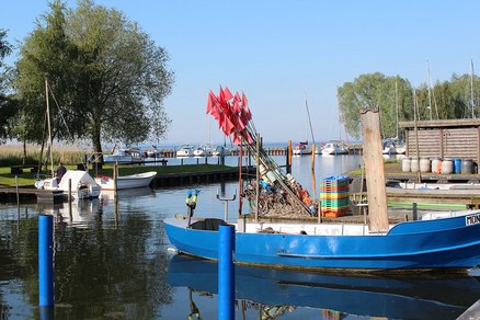 zeigt Blick auf den Fischereihafen mit blauem Fischerboot im Vordergrund