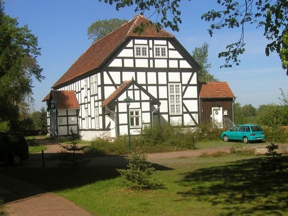 zeigt Außenansicht der angrenzenden Fachwerkkirche