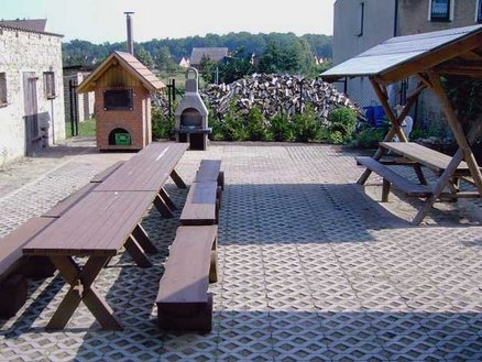 zeigt rückwärtigen Hofbereich mit Sitzelementen und Holzbackofen