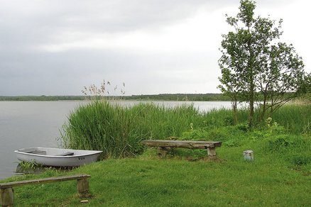 zeigt Blick auf den Neuwarper See bei Rehhagen mit einem kleinen Boot und Holzbänken am Ufer