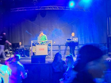zeigt Bühne mit DJ's und tanzenden Leuten davor