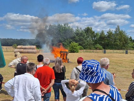zeigt Personengruppe, die ein brennendes Feuer betrachten