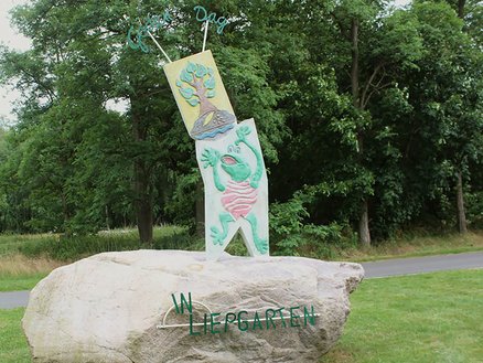 zeigt einen Findlingsstein mit einer Froschplastik darauf