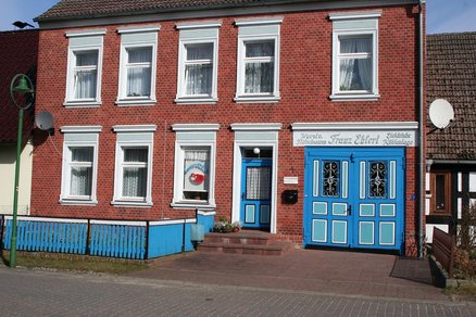 zeigt 2-geschossiges Gründerzeitgebäude aus rotem Klinker mit verzierten Fenster und Türen